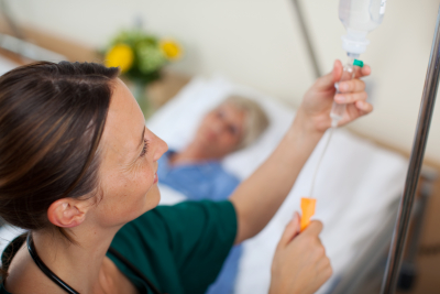 nurse adjusting infusion bottle with patient lying on bed