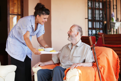 caregiver serving food to senior man